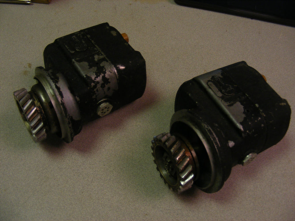 Two silver Slick magnetos, gear and shaft detail